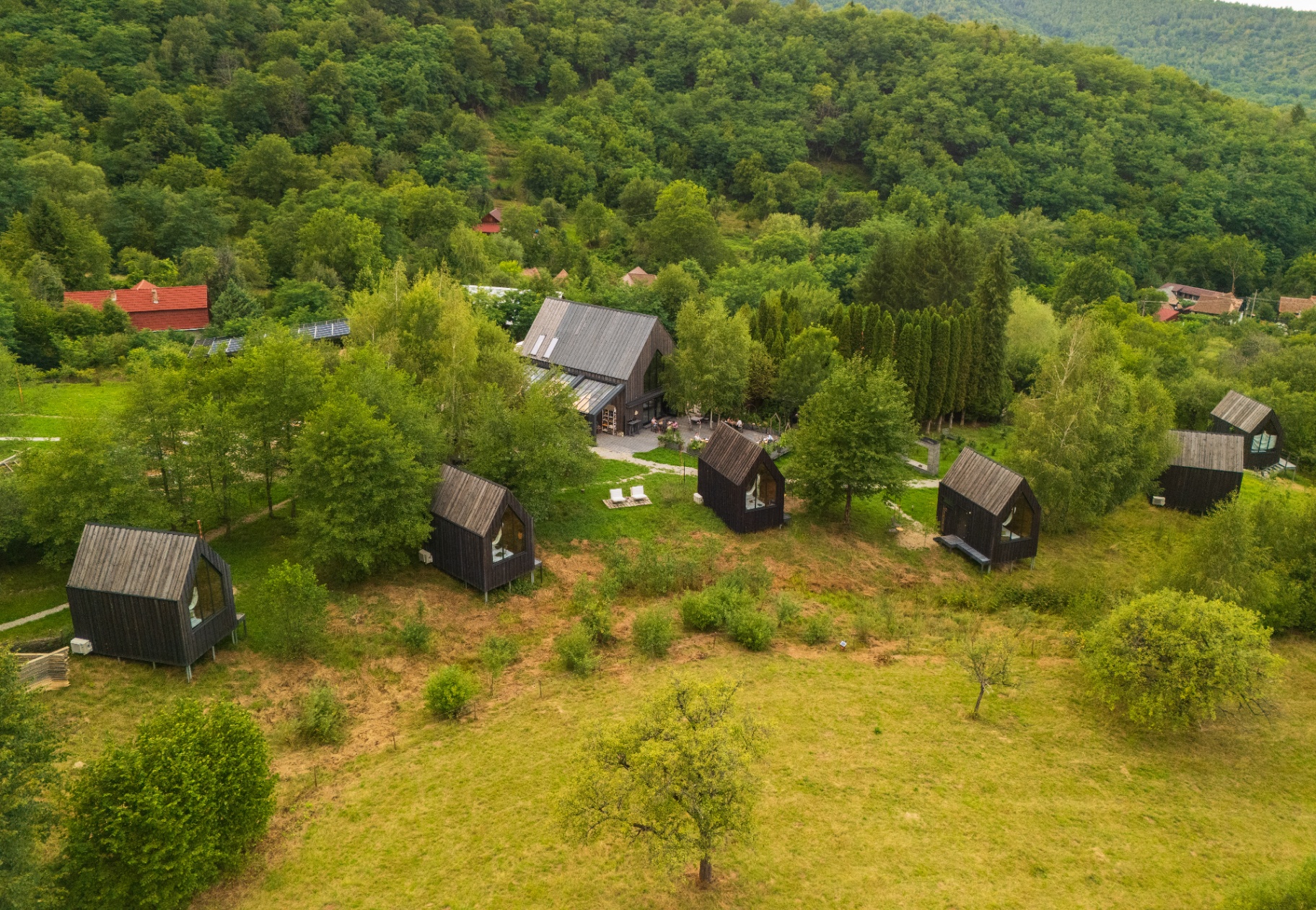 Vedere aeriană peste satul Portal, cu bungalourile pe deal și pădurea în jur