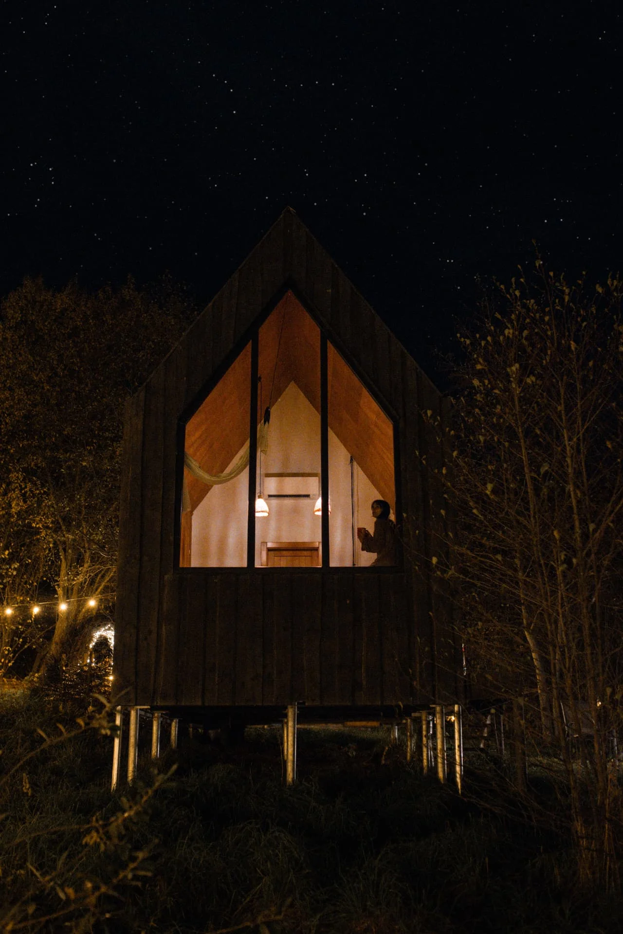 Bungalou în noapte, lumină caldă și stele